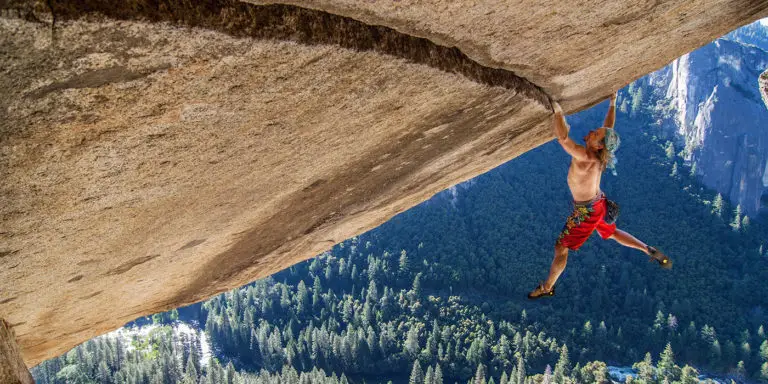 Fotografía de un hombre escalando una montaña sin cuerdas.