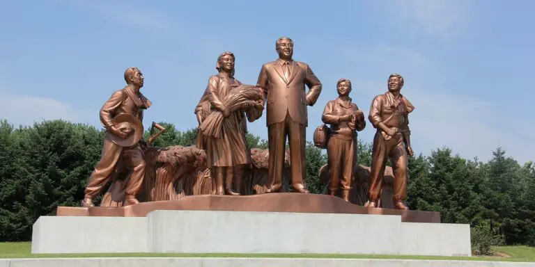 Estatua del dictador comunista norcoreano Kim Il-sung junto a un grupo de trabajadores norcoreanos.